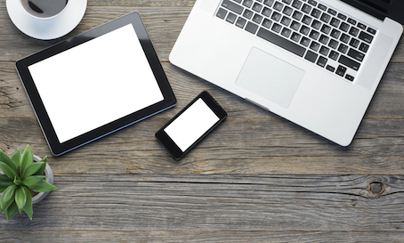 Digital tablet, laptop and smart phone on a wooden table. There is also coffee and a plant on the desk. Mobile devices are white blank. Copy space.